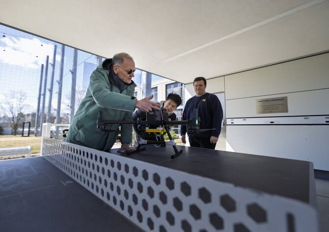 Chris Ruf, the Frederick Bartman Collegiate Professor of Climate and Space Sciences at U-M (left), prepares a drone that will validate the new FireSat’s soil moisture measurements for a test flight at the M-Air facility with research assistants Dinan Bai (middle) and Benjamen Miller (right). The recently-launched satellite is the first prototype of a constellation that could one day monitor wildfires from space. Photo credit: Jeremy Little, Michigan Engineering.
